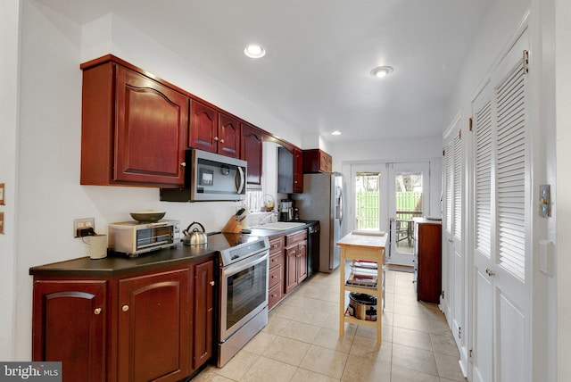 kitchen with dark countertops, recessed lighting, stainless steel appliances, a toaster, and light tile patterned floors