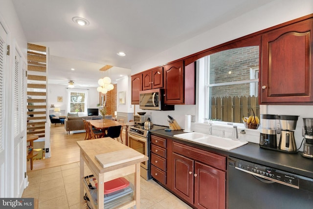 kitchen with dark countertops, open floor plan, recessed lighting, stainless steel appliances, and a sink