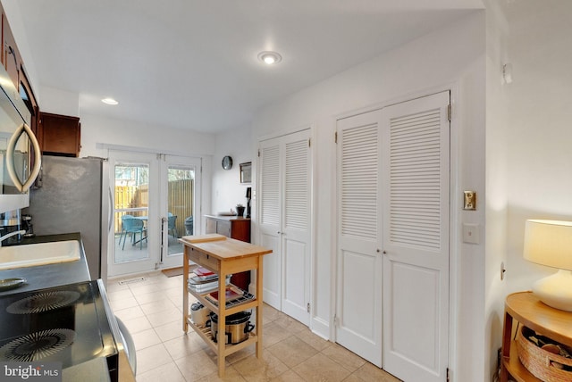 kitchen featuring light tile patterned floors, recessed lighting, freestanding refrigerator, and a sink