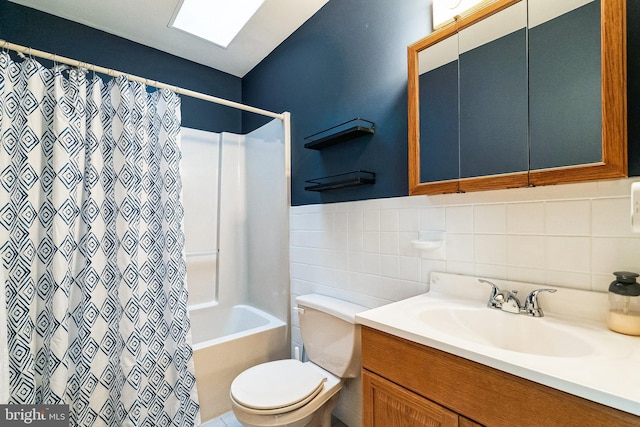 bathroom with vanity, shower / bath combination with curtain, wainscoting, tile walls, and toilet