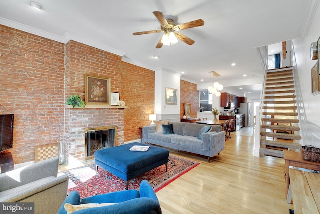 living area with light wood-type flooring, stairway, a fireplace, and crown molding