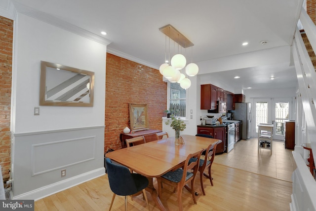 dining room featuring brick wall, recessed lighting, wainscoting, crown molding, and light wood-type flooring