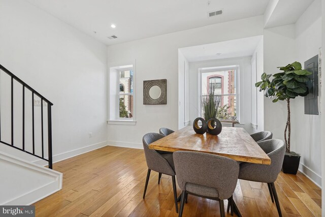 dining room featuring visible vents, stairway, baseboards, and light wood-style floors