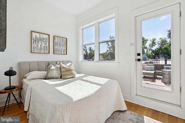 bedroom with multiple windows, wood finished floors, and baseboards