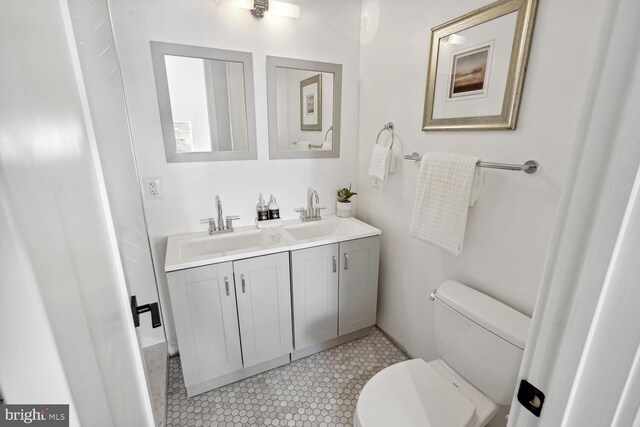 bathroom featuring double vanity, toilet, and a sink