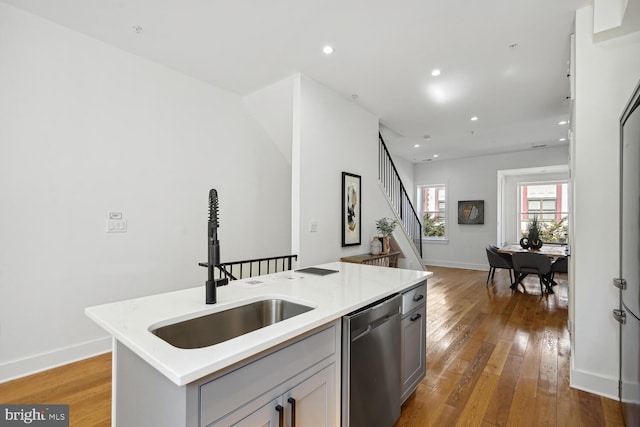 kitchen featuring a sink, hardwood / wood-style floors, light countertops, and stainless steel dishwasher