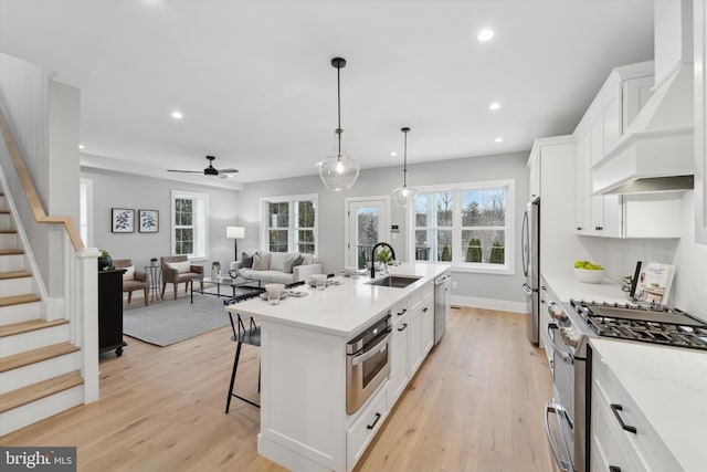 kitchen with a breakfast bar area, appliances with stainless steel finishes, custom exhaust hood, white cabinets, and a sink