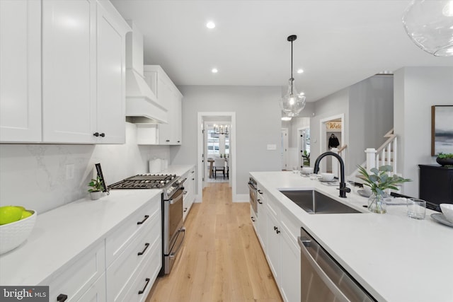 kitchen featuring premium range hood, a sink, white cabinetry, appliances with stainless steel finishes, and decorative backsplash