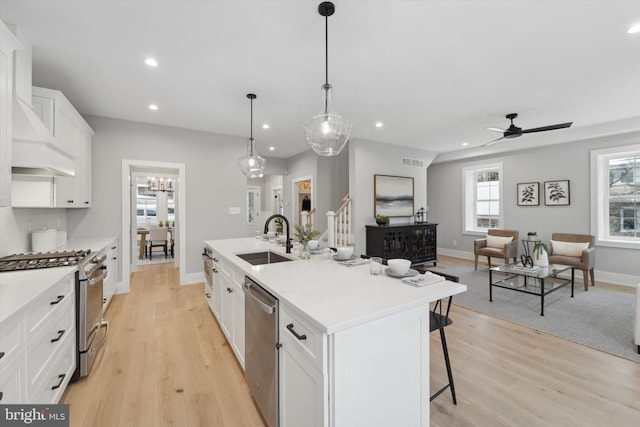 kitchen with visible vents, a breakfast bar, a center island with sink, a sink, and stainless steel appliances