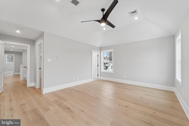 spare room with visible vents, baseboards, light wood-style floors, and vaulted ceiling