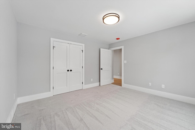 unfurnished bedroom featuring carpet flooring, baseboards, and a closet