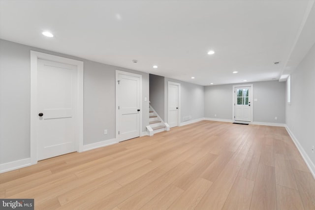 below grade area featuring recessed lighting, stairs, and light wood-style floors