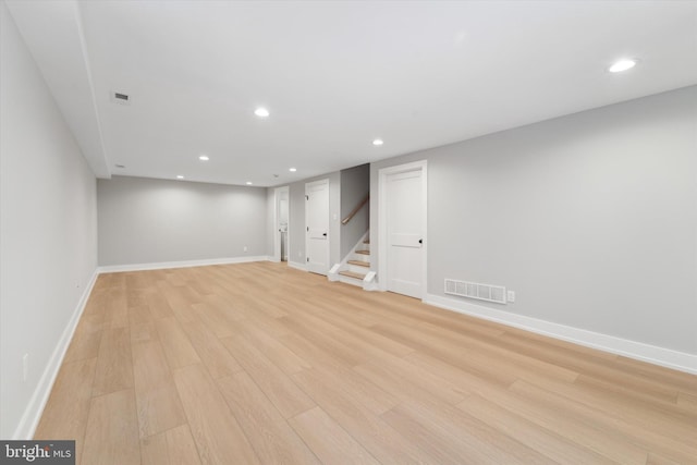 finished below grade area with visible vents, light wood-style flooring, recessed lighting, baseboards, and stairs