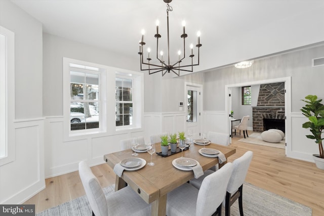 dining area featuring a stone fireplace, light wood-style floors, and a wealth of natural light