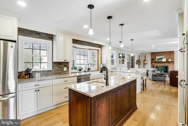 kitchen featuring a wealth of natural light, a center island with sink, stainless steel appliances, and crown molding