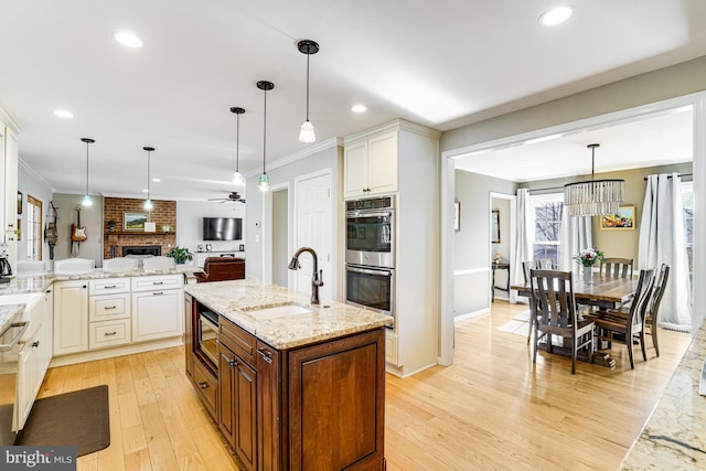 kitchen featuring light stone countertops, ornamental molding, a sink, appliances with stainless steel finishes, and open floor plan