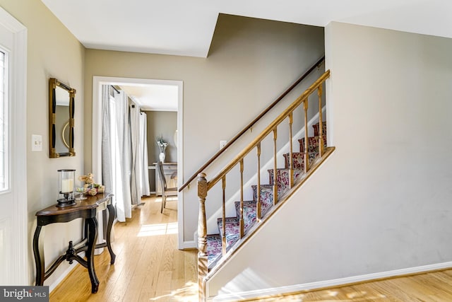 staircase featuring wood finished floors and baseboards