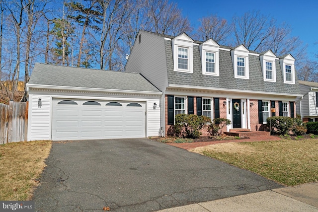 view of front facade featuring fence, driveway, roof with shingles, an attached garage, and brick siding