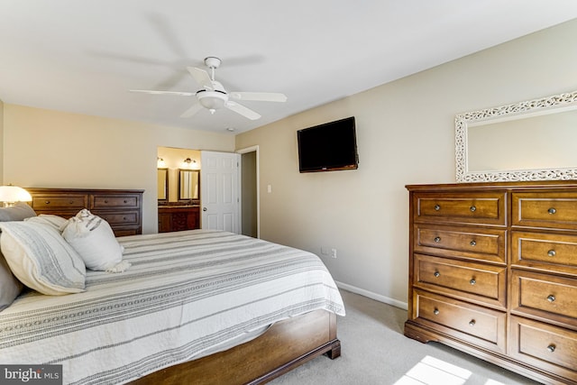 bedroom with light colored carpet, connected bathroom, baseboards, and ceiling fan