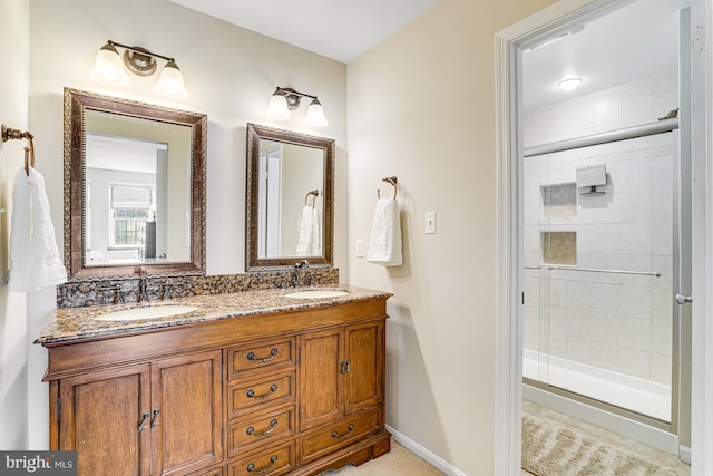 bathroom featuring double vanity, tiled shower, baseboards, and a sink