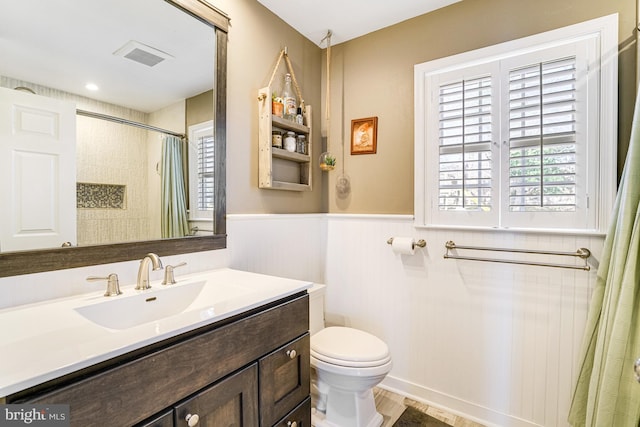 bathroom featuring vanity, a shower with curtain, visible vents, wainscoting, and toilet