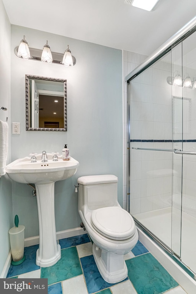 bathroom with baseboards, toilet, and a shower stall