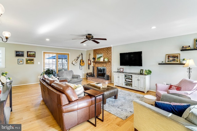 living area featuring a fireplace, ceiling fan, light wood-style floors, and ornamental molding