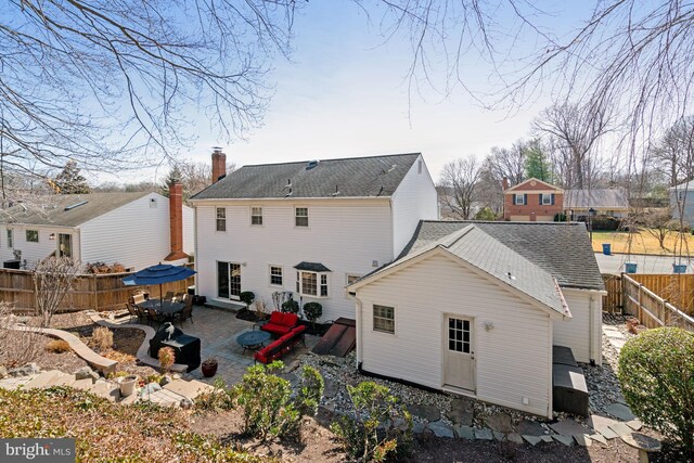 back of property with a patio area, fence, and roof with shingles