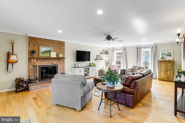 living area with light wood-type flooring, ornamental molding, a ceiling fan, recessed lighting, and a brick fireplace