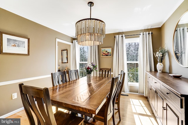 dining room with crown molding, light wood-style flooring, baseboards, and a chandelier