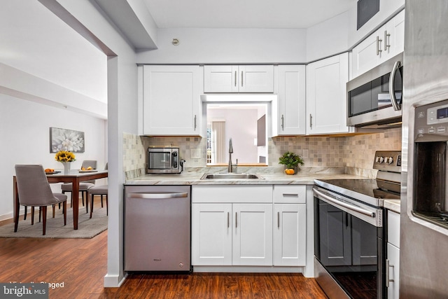 kitchen with a sink, light countertops, white cabinets, stainless steel appliances, and dark wood-style flooring