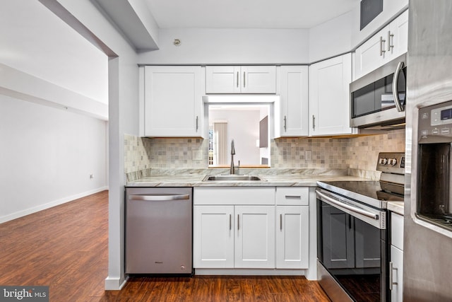 kitchen with a sink, dark wood-type flooring, appliances with stainless steel finishes, and white cabinets