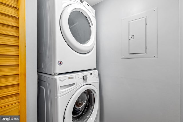 washroom featuring laundry area, stacked washer / dryer, and electric panel