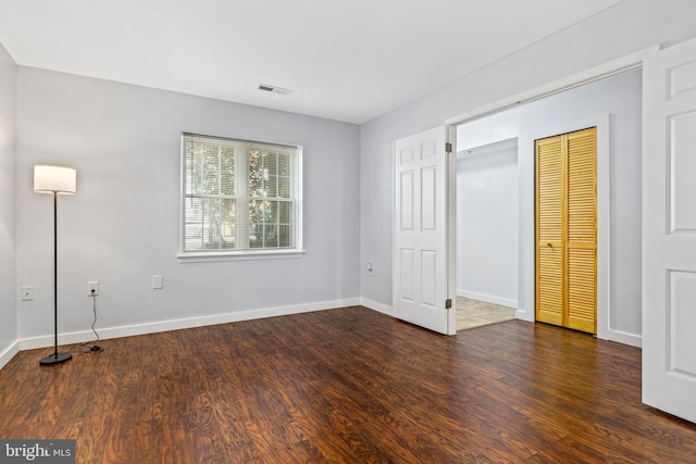 unfurnished bedroom with visible vents, baseboards, a closet, and wood finished floors