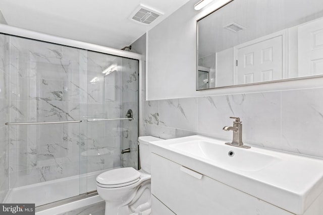 full bath featuring a marble finish shower, visible vents, toilet, and vanity