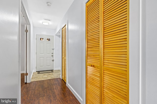 hall with visible vents, baseboards, and dark wood finished floors