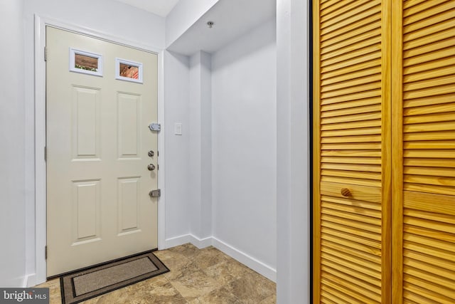 foyer with stone finish flooring and baseboards