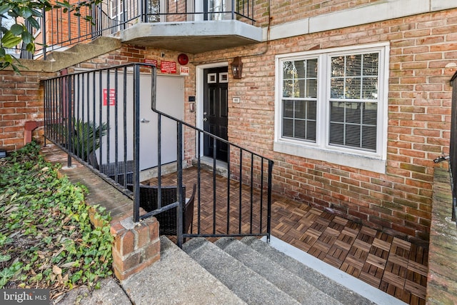 view of exterior entry with a balcony and brick siding