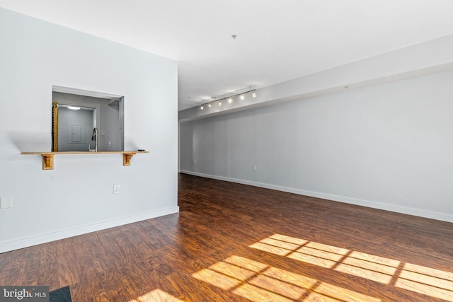 unfurnished living room featuring track lighting, a sink, baseboards, and wood finished floors