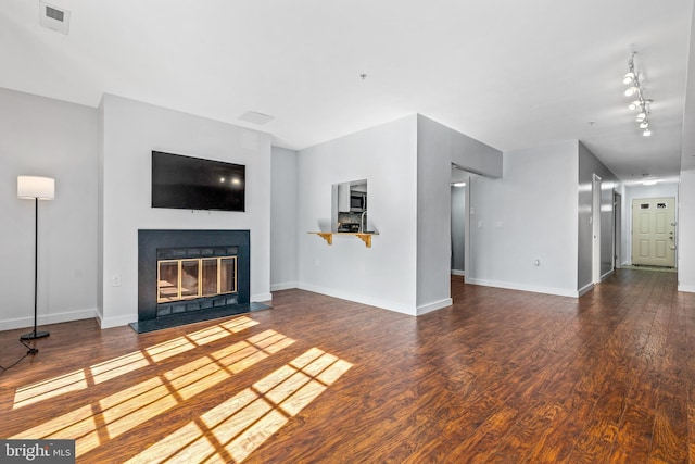 unfurnished living room with visible vents, a fireplace with flush hearth, wood finished floors, and baseboards