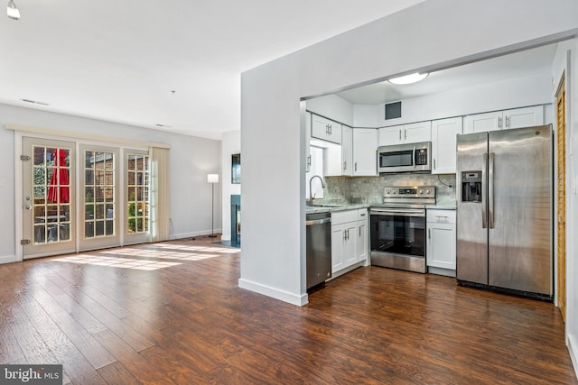 kitchen featuring dark wood finished floors, a sink, stainless steel appliances, light countertops, and backsplash