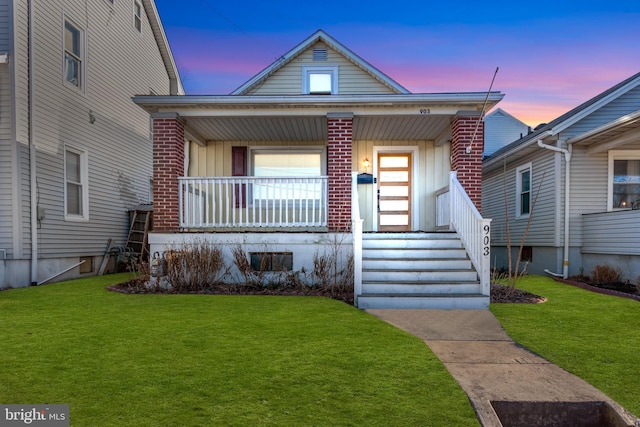 view of front of house with brick siding, a porch, and a front yard