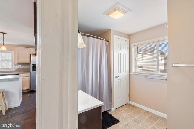 bathroom with a wealth of natural light, decorative backsplash, baseboards, and a shower with curtain