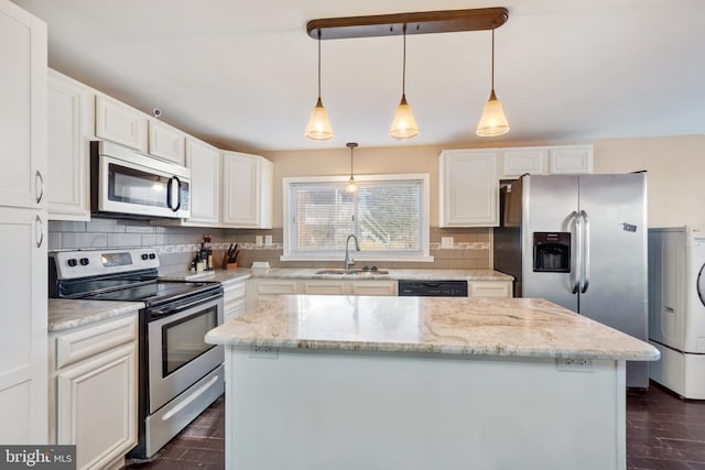 kitchen featuring a sink, washer / clothes dryer, a kitchen island, tasteful backsplash, and appliances with stainless steel finishes