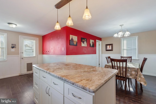 kitchen featuring a wainscoted wall, white cabinetry, dark wood-style flooring, and hanging light fixtures