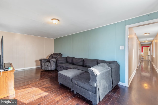 living room with hardwood / wood-style flooring, a decorative wall, and baseboards