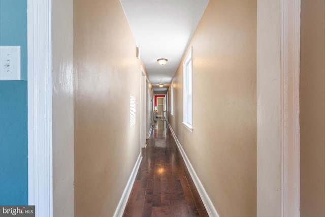 corridor featuring baseboards and dark wood-style floors