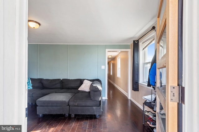 living area featuring a decorative wall, baseboards, and hardwood / wood-style floors