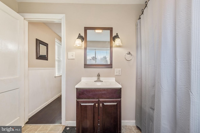 bathroom featuring vanity, curtained shower, and baseboards