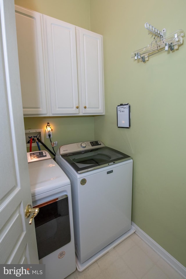 laundry area featuring washer and dryer, cabinet space, and baseboards